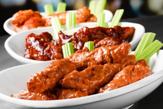 3 plates of zingers that's smothered with sauce and side of celery